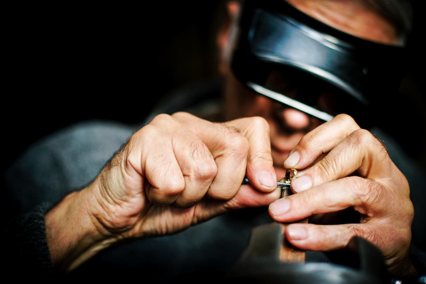 A goldsmith shaping a ring by hand under a loupe at the Simoni Gold bench